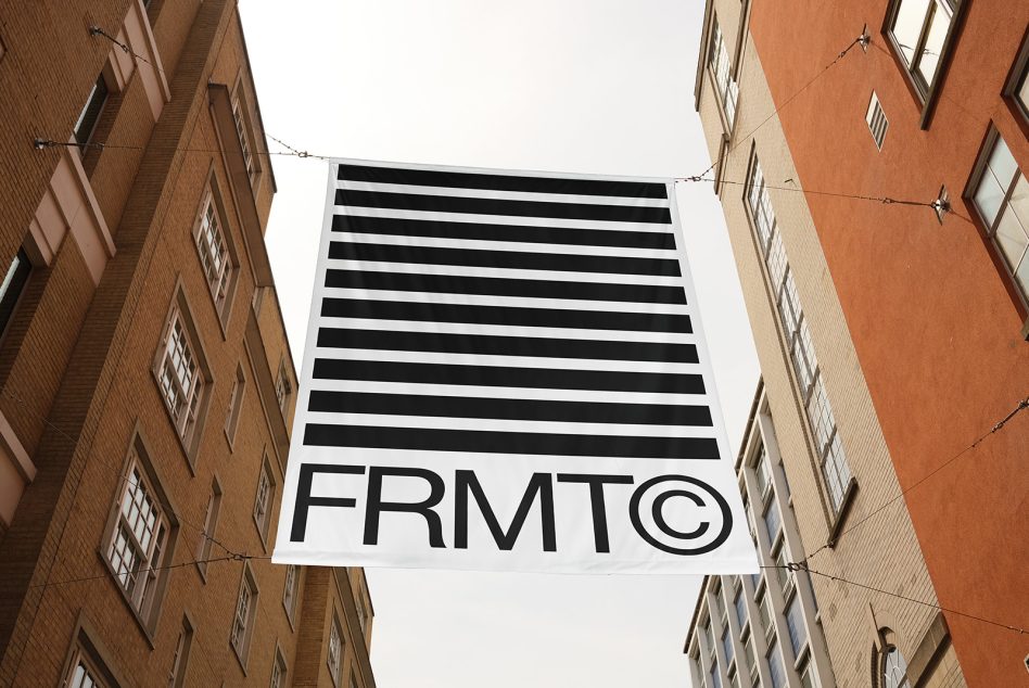 Urban banner mockup with black and white striped design and FRMT logo hanging between two brick buildings, clear for brand presentation.