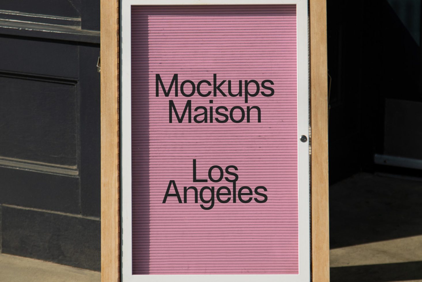 Sandwich board sign mockup featuring bold text "Mockups Maison Los Angeles" with a textured pink background, ideal for outdoor advertising designs.