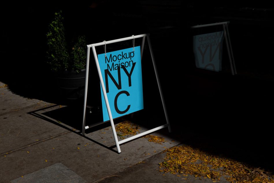 Sidewalk signboard mockup with cyan 'NYC' design on display, urban setting, design template for branding and advertising.