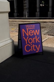 Sandwich board on street with purple background, orange lettering