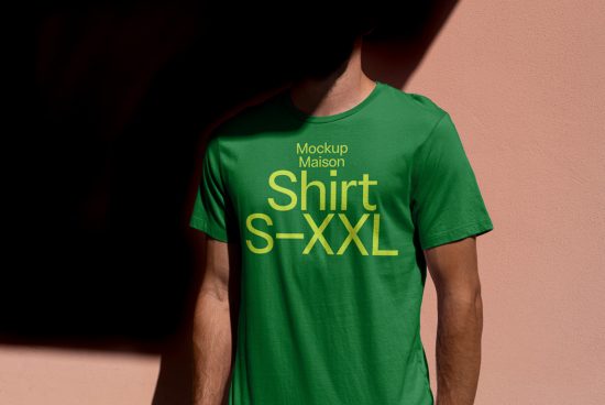 Green t-shirt mockup on man against pink wall for apparel design presentation, including size label, realistic shadows, fashion, textile.