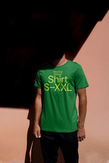 Man in green t-shirt mockup with text design, ideal for presentations, on a pink background with shadow play.