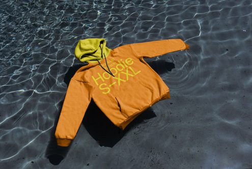 Orange and lime hoodie mockup floating on water texture, realistic apparel design presentation, fashion graphic display.