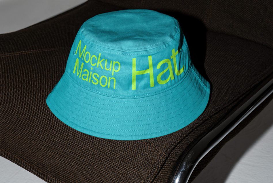 Turquoise bucket hat with yellow text on black chair mockup