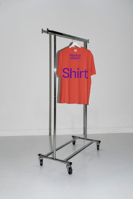 Red t-shirt mockup on metal hanger stand with wheels in a neutral setting, ideal for apparel design presentation.