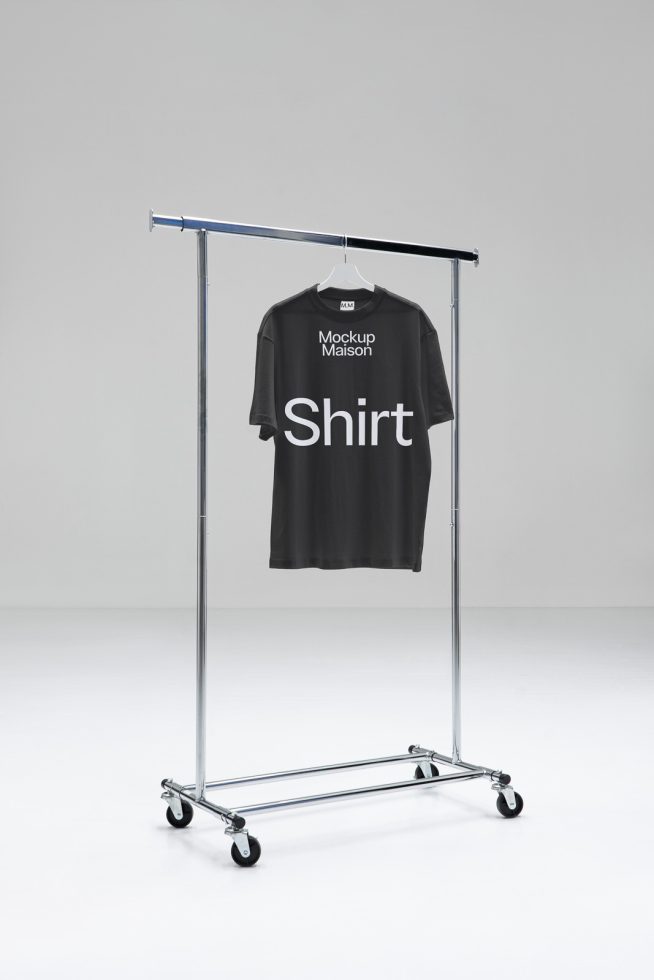 Black t-shirt on hanger with plain design, mockup ready for graphics display on a metal clothing rack against a neutral background.