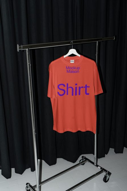 Red t-shirt mockup on hanger with black curtain background, ideal for apparel design presentation in graphic work.