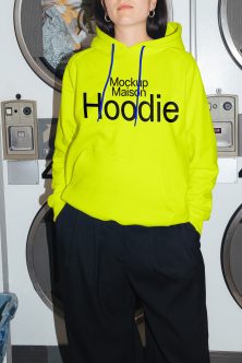 Neon yellow hoodie with blue drawstrings worn in laundromat setting