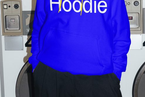 Blue hoodie apparel mockup with text design, on model in urban laundry setting, for graphic designers, editable clothing template.