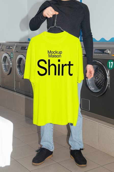 Person holding neon yellow t-shirt mockup in laundromat setting, ideal for apparel design showcasing, t-shirt template display, realistic clothing mockup.