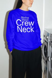 Woman in royal blue crewneck sweatshirt standing by washing machine side profile