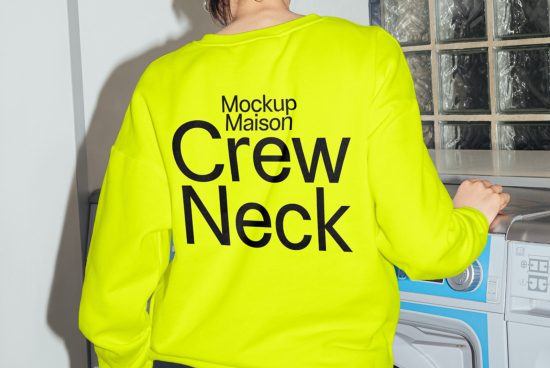 Bright yellow crew neck sweatshirt mockup with bold black text on model in a laundromat setting, ideal for clothing design presentations.