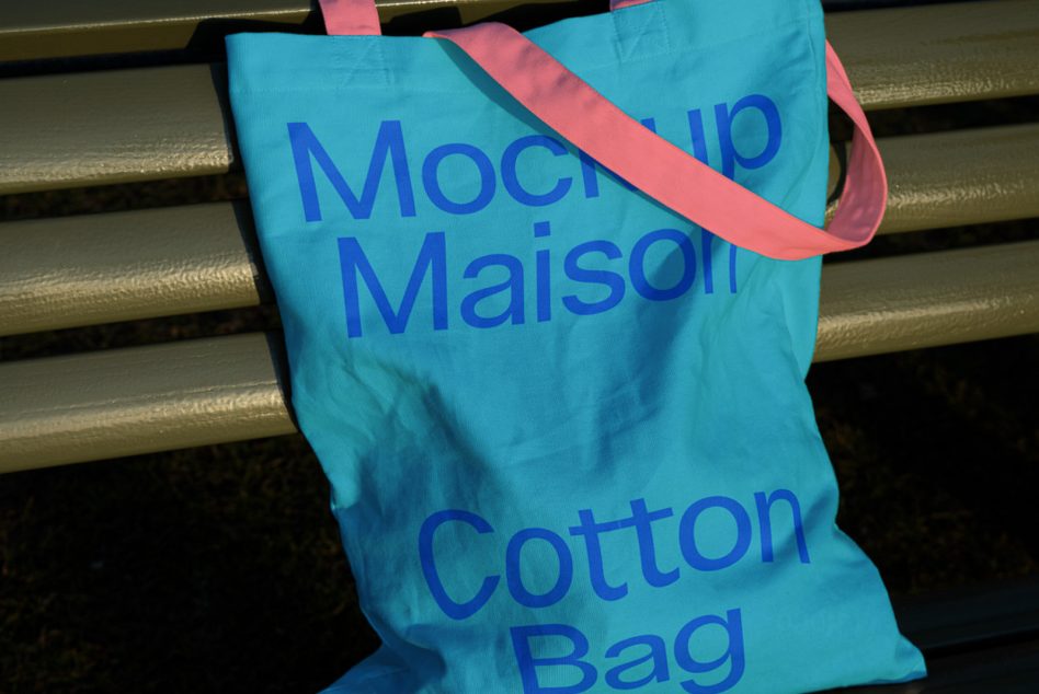 Turquoise shopping bag with blue text, pink handles hanging on rod