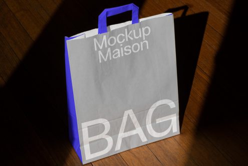 Paper shopping bag mockup with shadows on a wooden floor, ideal for branding presentations and packaging designs.