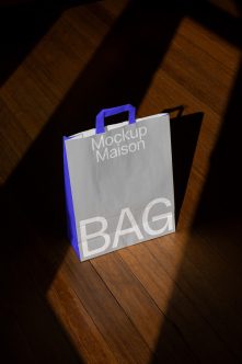 Shopping bag with vibrant blue sides, white front, blue handles on wood surface