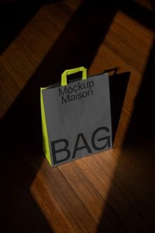 Shopping bag with bright lime green sides, gray front, black handles on wooden floor