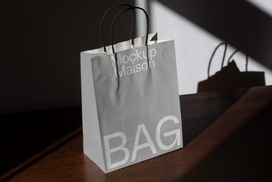 Paper shopping bag mockup in sunlight with strong shadow, ideal for presenting branding and packaging designs.