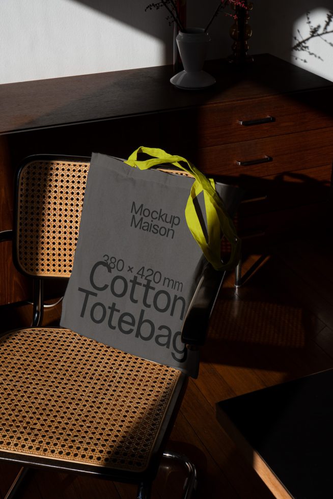 Elegant tote bag mockup on chair in sunlit room, ideal for presenting design projects, eco-friendly bag designs, trendy and realistic setting.