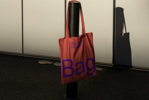 Tote bag mockup hanging on a pole outdoor, showcasing typography design for print, realistic shadows, ideal for graphics and templates display.