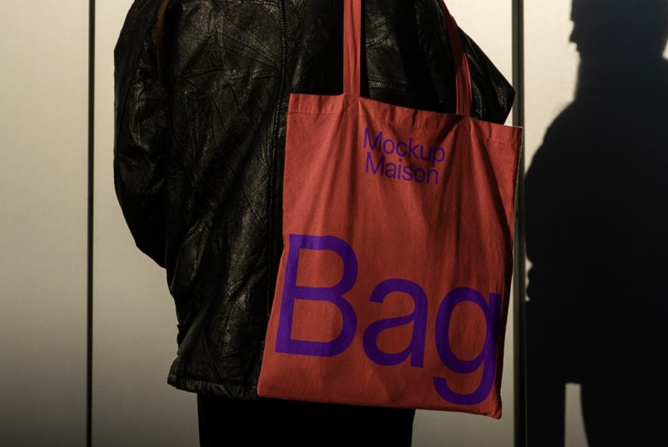 Red canvas tote bag with blue text worn over black leather jacket