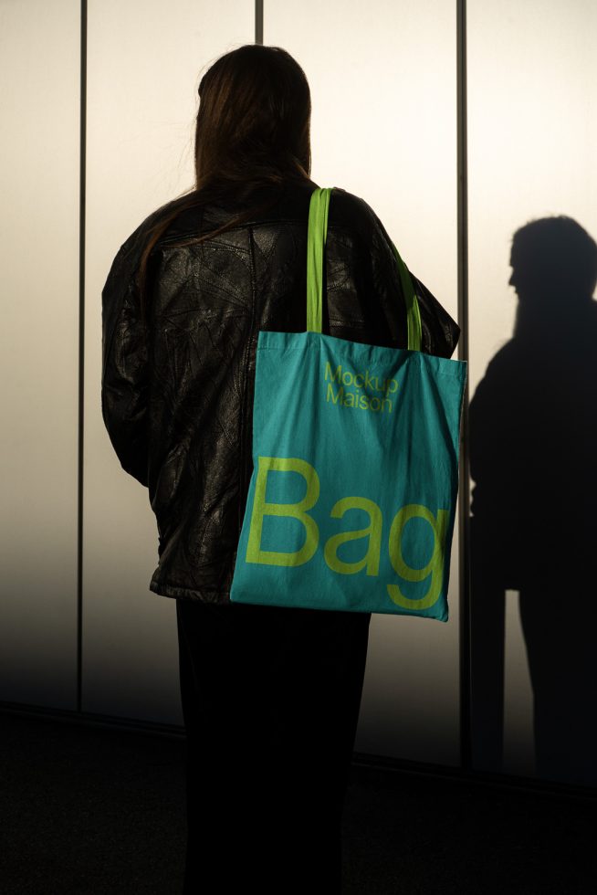 Woman standing holding a tote bag with mockup text, ideal for showcasing bag designs, suitable for graphics and templates category.