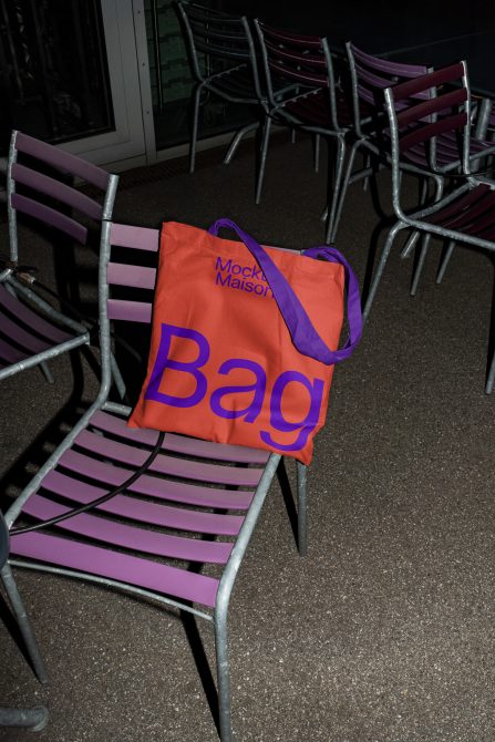 Tote bag mockup on purple metal chair, outdoor setting at night, ideal for showcasing design work, related to mockups and branding assets.