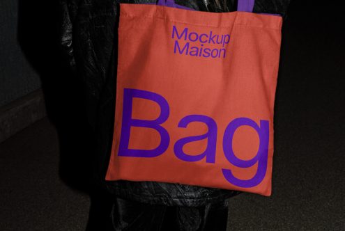 Person holding a tote bag mockup in orange with bold blue 'Bag' text, ideal for design presentations and templates.