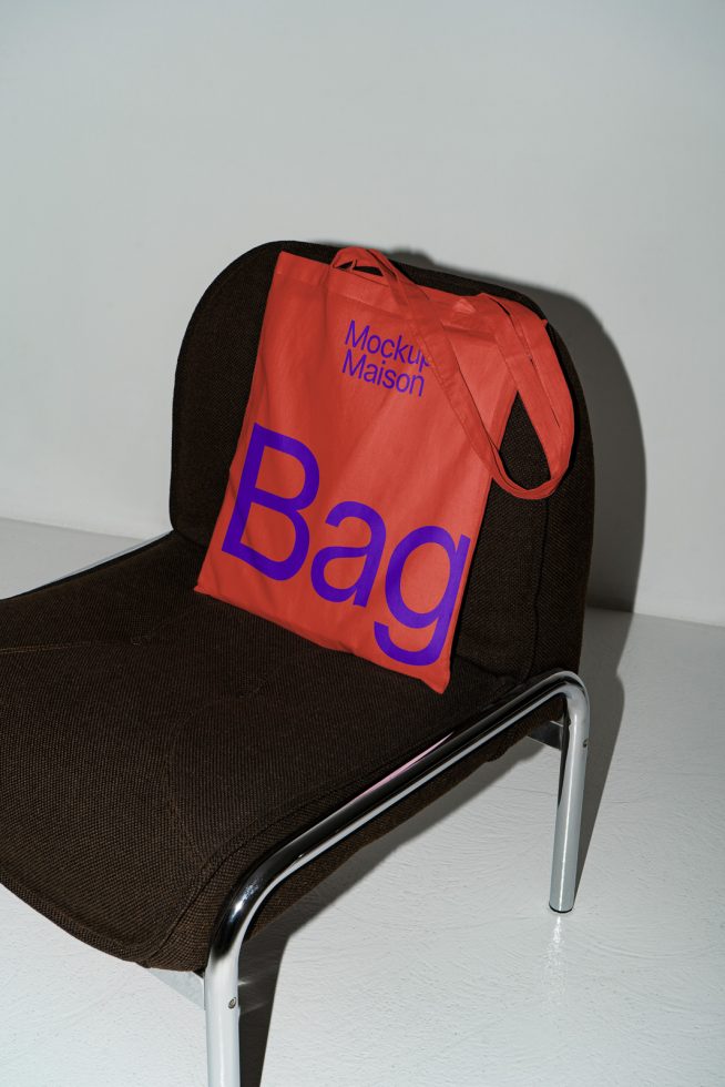 Vibrant tote bag mockup on modern chair, clear shadow, trendy design presentation, digital asset for graphic designers.