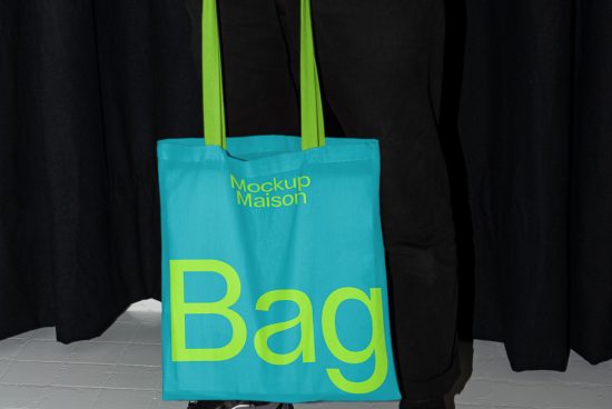 Bright blue tote bag mockup hanging against a dark curtain background, showcasing design space for graphics and typography.