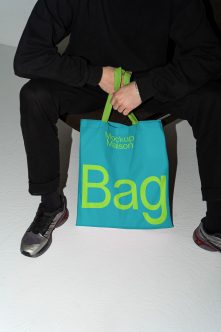 Person holding turquoise tote bag with lime handles