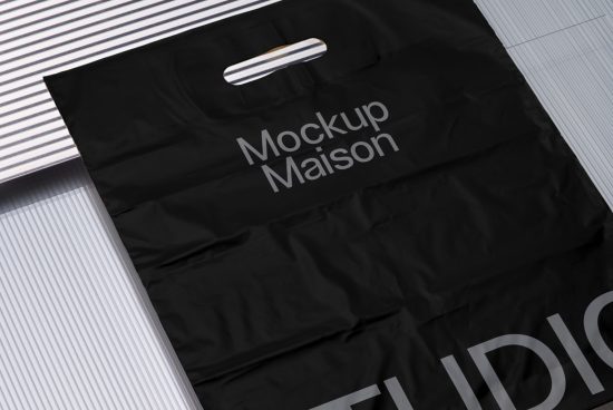 Black tote bag mockup with handle on striped background, showcasing design space for branding, ideal asset for graphic designers.