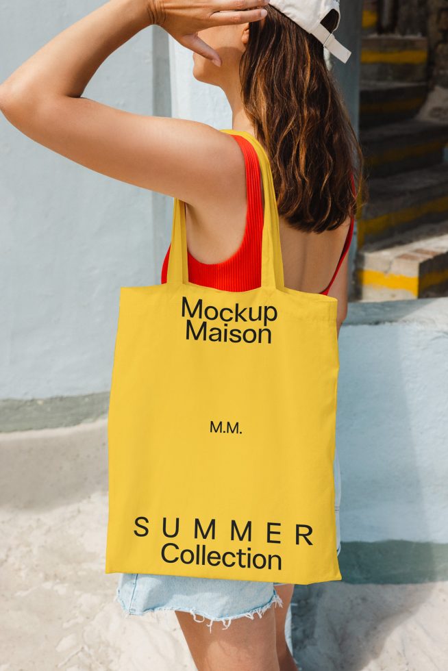 Woman in summer outfit holding a yellow tote bag mockup with text design, ideal for showcasing brand graphics and designs.