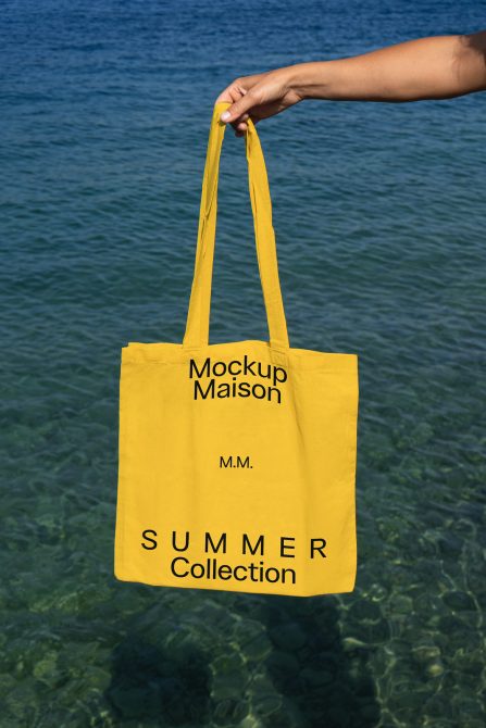 Yellow tote bag mockup held over clear water, ideal for showcasing summer collection designs, great for designers in mockups category.