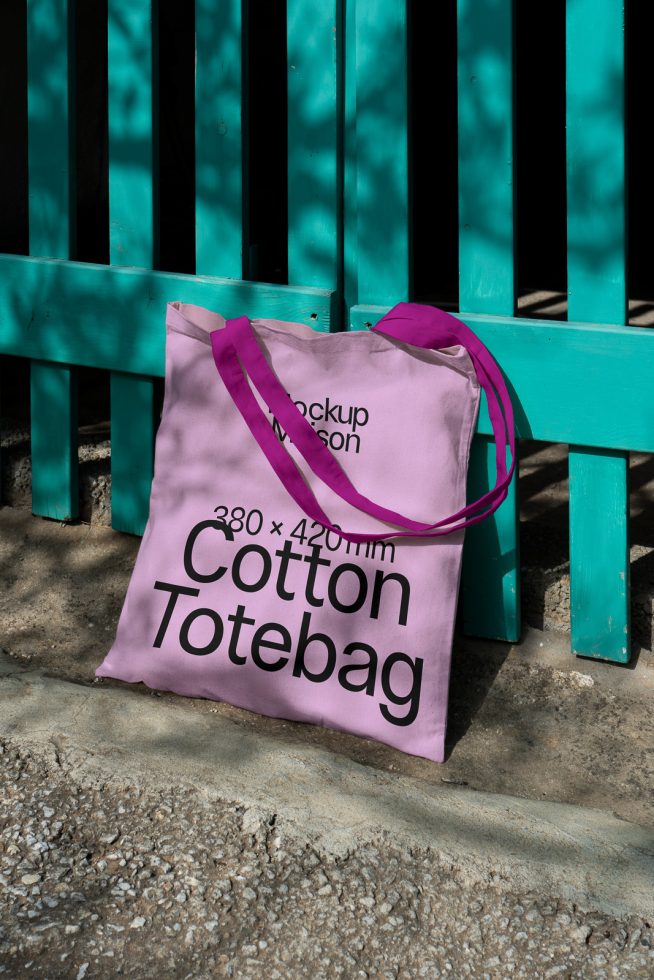 Purple cotton tote bag mockup against a turquoise bench outdoor setting, showcasing design space and product dimensions for designers.