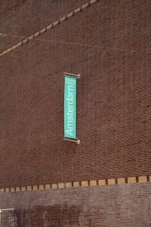 Vertical turquoise banner hanging on brick wall with Amsterdam text