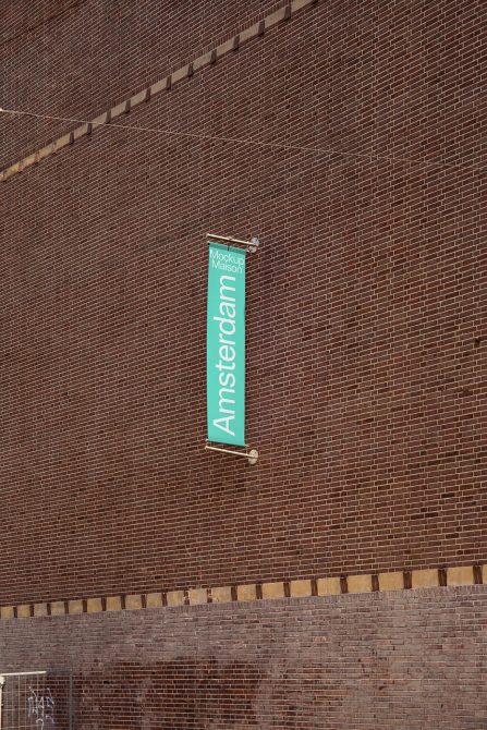 Vertical turquoise banner hanging on brick wall with Amsterdam text