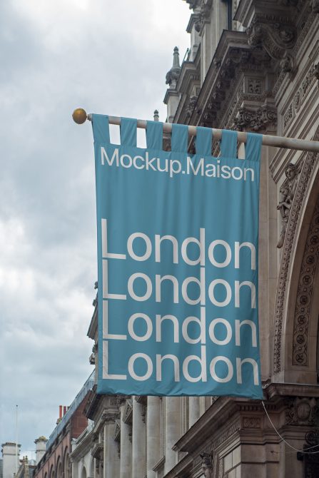 Blue banner mockup with text Mockup.Maison and London repeated, hanging on classic building, clear sky, urban design mockups category.