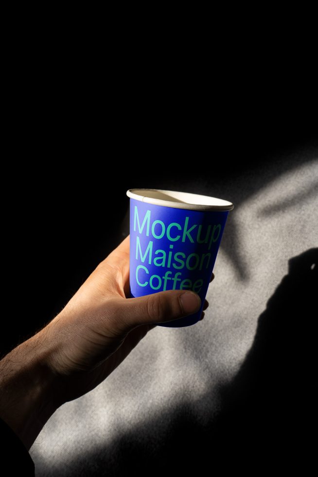 Hand holding coffee cup mockup with dynamic shadow, ideal for brand presentations and design showcases in the Mockups category.