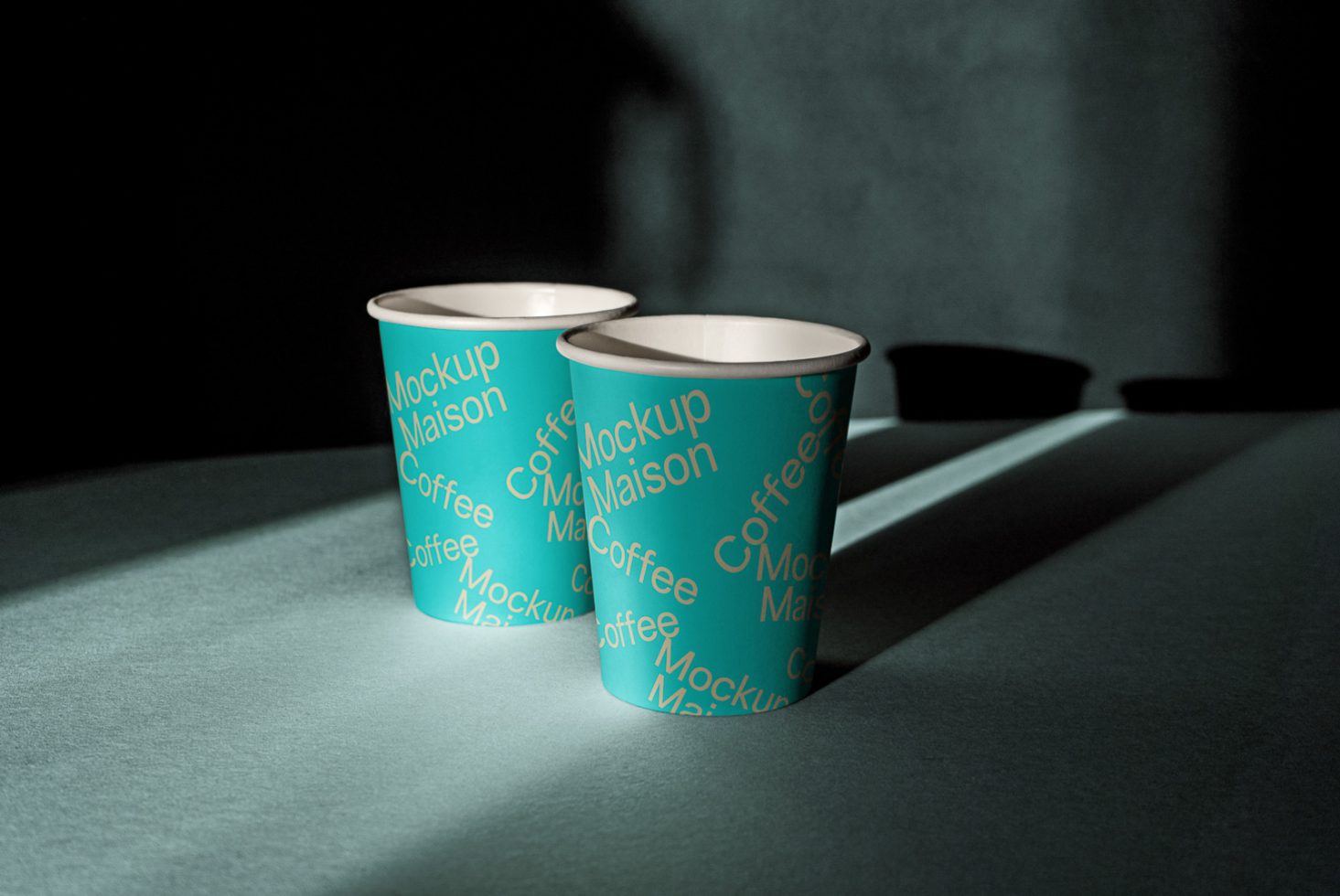 Two paper cup mockups in dramatic lighting for brand design showcase, perfect for graphic designers to display logos or patterns.