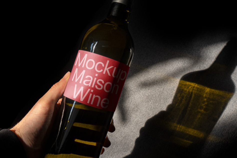 Hand holding a wine bottle mockup with label design under natural lighting, dynamic shadows, ideal for presentation in design templates.