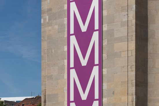 Vertical banner mockup with double M logo, urban setting with clear blue sky, suitable for graphic design display.
