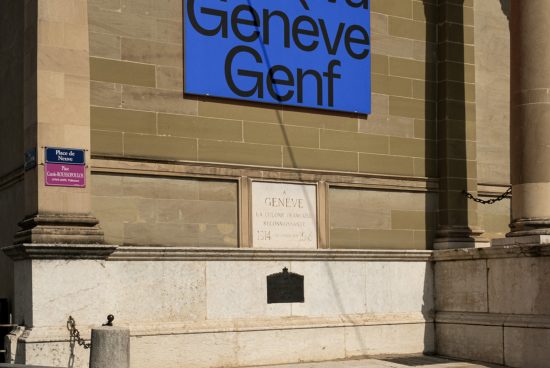 Sunlight casting shadow on historic building with Geneve sign, suitable for Graphics category or urban Template design inspiration.