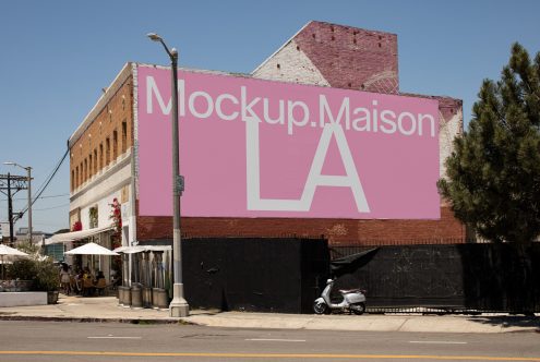 Urban billboard mockup on building side with clear sky, ideal for showcasing outdoor advertising designs in a realistic setting.