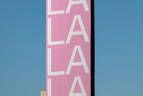 Bold white text "LA LA LA" on pink banner, clear blue sky background, ideal for graphic design mockups, urban aesthetics, typography.