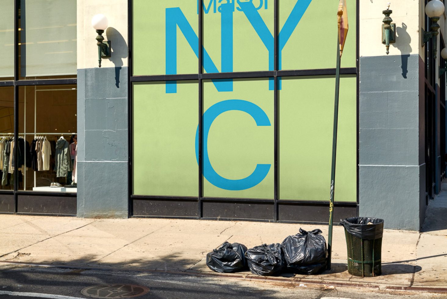 Urban storefront window graphics design mockup with bold typography and street elements like trash bags for designers to showcase branding work.