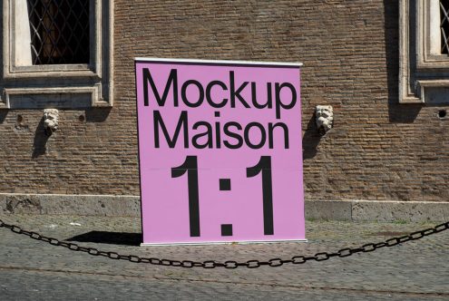 Outdoor poster mockup on historic building wall featuring a pink sign with the text Mockup Maison, ideal for showcasing design projects.