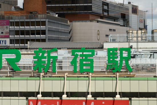 Urban Japanese signage mockup showcasing large green lettering with cityscape background for designers and advertising.