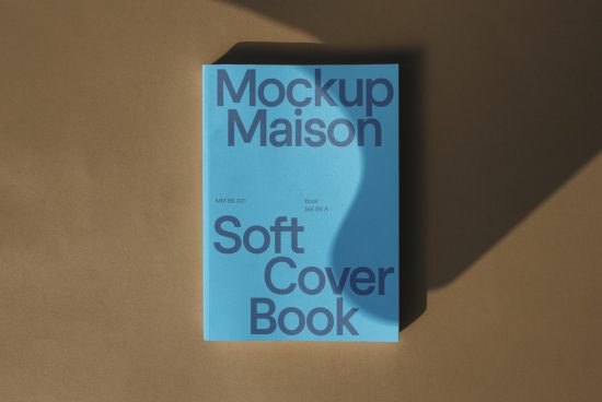 Blue softcover book mockup on brown background with natural shadows, ideal for designers to showcase their work in graphics and templates.