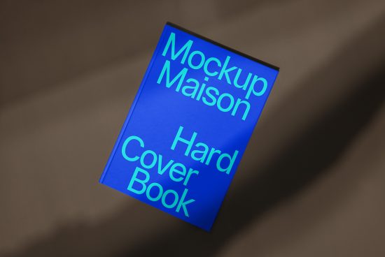 Blue hardcover book mockup laying on a textured surface with dramatic lighting, ideal for presentation, eBook cover design, and portfolios.