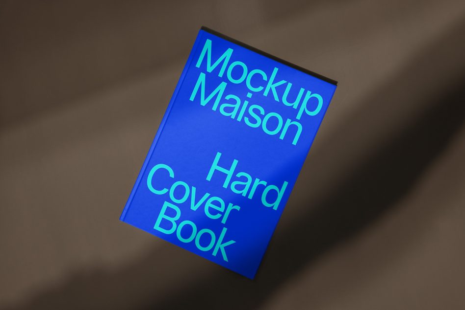 Blue hardcover book mockup laying on a textured surface with dramatic lighting, ideal for presentation, eBook cover design, and portfolios.